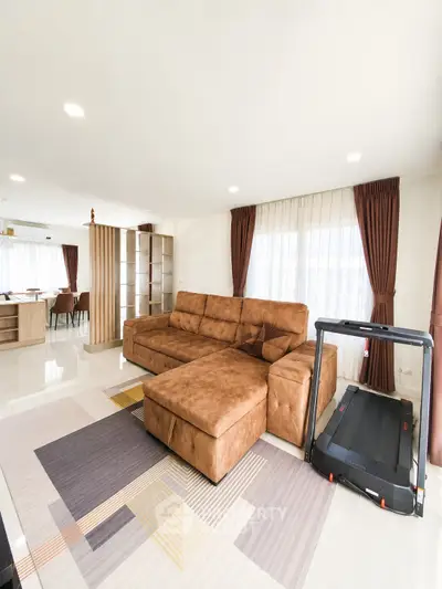 Spacious living room with modern brown sofa and treadmill, featuring elegant curtains and open layout.