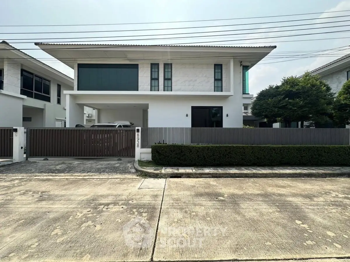 Modern two-story house with sleek design and gated entrance in a suburban neighborhood.