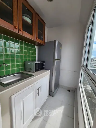 Compact kitchen with green tile backsplash and large window view