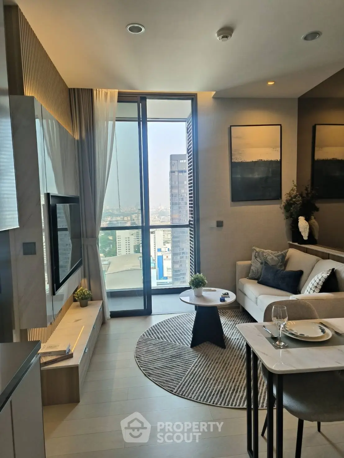 Modern living room with city view, stylish decor, and cozy seating area in a high-rise apartment.