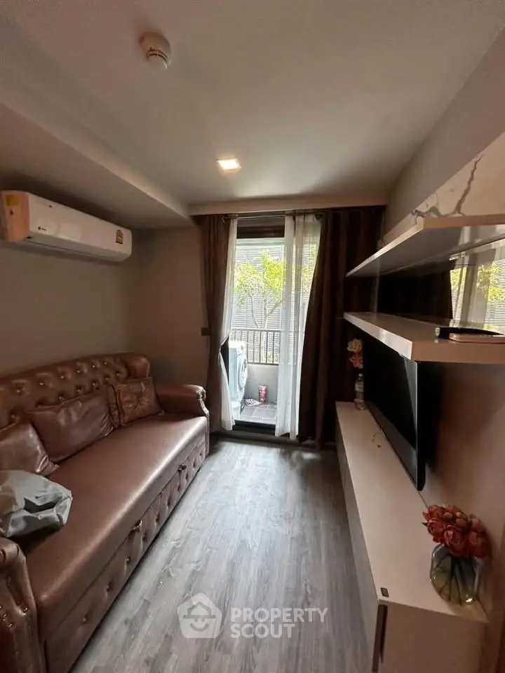 Cozy living room with modern decor and balcony view, featuring a plush sofa and wall-mounted TV.