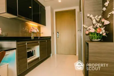 Modern kitchen with sleek dark cabinetry, built-in oven, and vibrant floral accents creating a warm, inviting atmosphere for culinary enthusiasts.