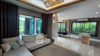 Spacious modern living room with elegant decor and large windows offering lush garden views.