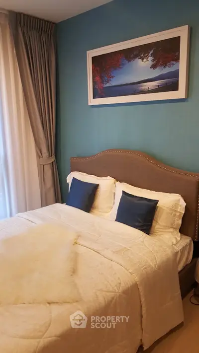 Cozy bedroom with elegant decor and natural light, featuring a plush bed and stylish artwork.