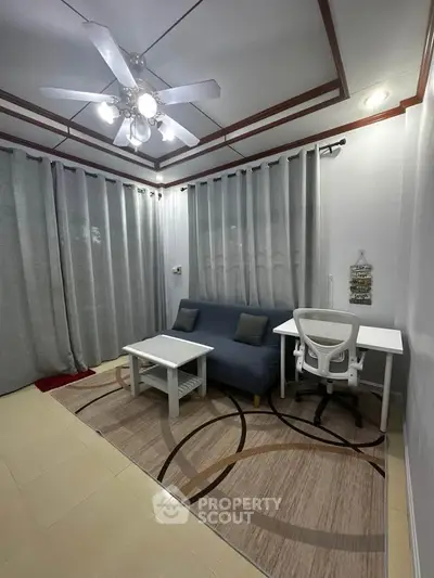 Cozy living room with modern decor and study area, featuring a ceiling fan and stylish curtains.