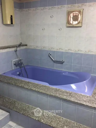 Spacious bathroom with unique blue bathtub and tiled walls, perfect for relaxation.