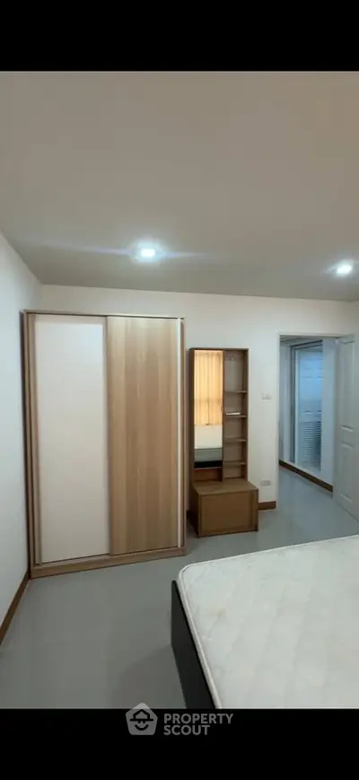 Spacious bedroom with modern wardrobe and cozy lighting, perfect for relaxation.