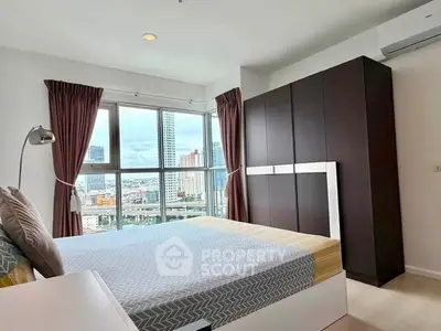 Modern bedroom with city view, featuring large windows and stylish furniture.
