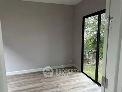 Spacious empty room with large window and garden view, perfect for customization.