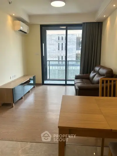 Modern living room with balcony view, featuring sleek furniture and natural light.