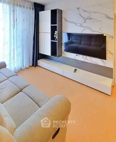 Modern living room with stylish TV unit and comfortable sofa, featuring elegant marble wall design.