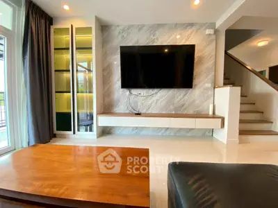 Modern living room with sleek TV setup and elegant staircase