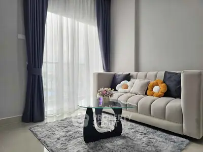 Stylish living room with modern sofa, glass coffee table, and plush rug in bright natural light.