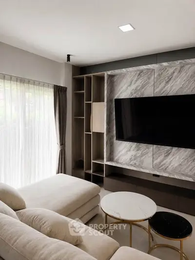 Modern living room with elegant marble wall, large TV, and cozy sectional sofa.