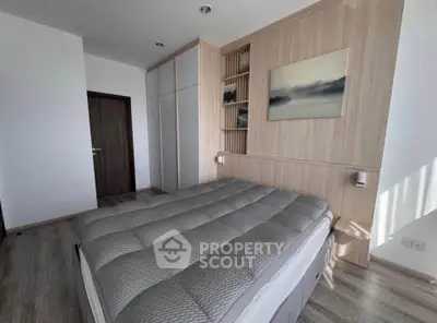 Modern bedroom with stylish wooden paneling and cozy bedding in a contemporary apartment.