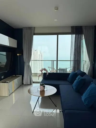Modern living room with large windows and balcony offering stunning city views.