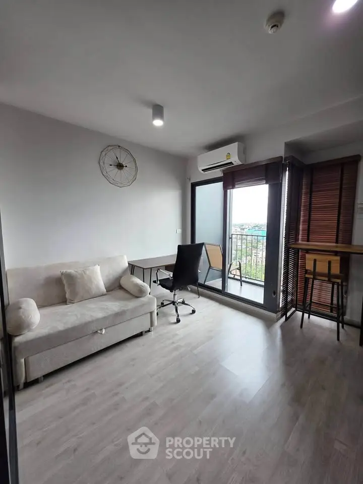 Modern living room with balcony view, featuring sleek furniture and natural light.