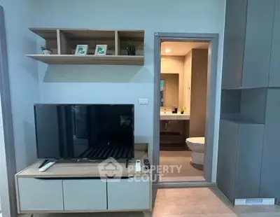 Modern living room with TV and open view into a sleek bathroom.