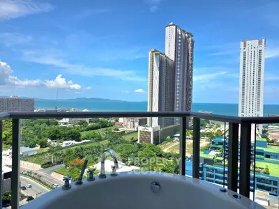 Luxurious balcony with bathtub offering stunning ocean and city skyline views.