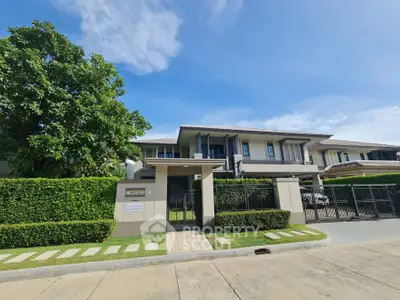 Luxurious modern house with lush greenery and gated entrance in a serene neighborhood.