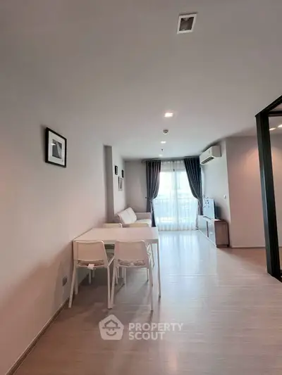 Modern living room with sleek design, featuring a cozy sofa, dining table, and large window with curtains.