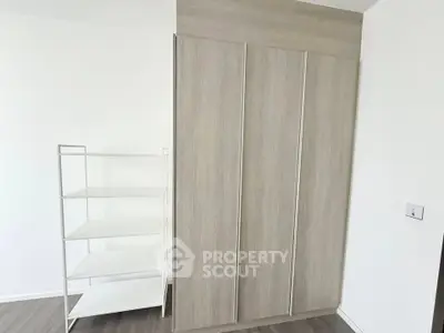 Modern minimalist interior with sleek wardrobe and shelving unit in a bright room.