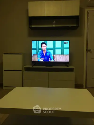 Cozy living room with modern TV setup and stylish furniture, perfect for relaxation.