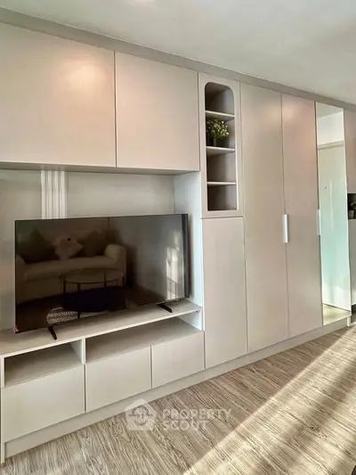 Modern living room with sleek built-in storage and TV unit, showcasing minimalist design and functionality.