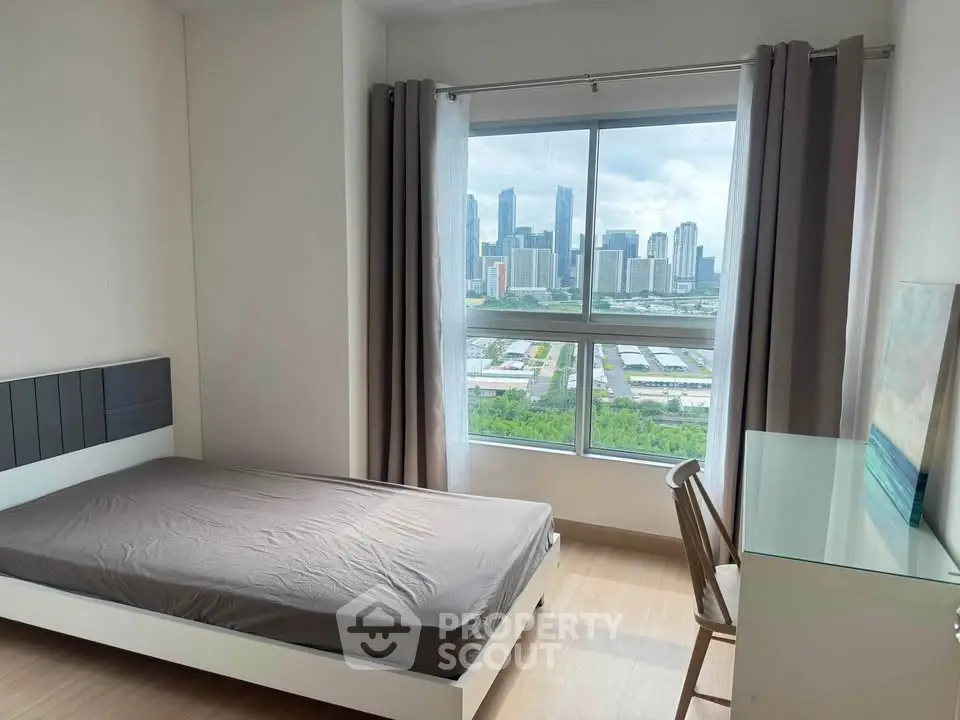 Modern bedroom with city skyline view, featuring a single bed and study desk, ideal for urban living.