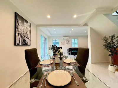 Elegant dining area with glass table and modern decor in a spacious open-plan living space.