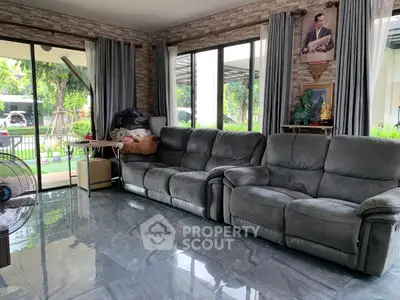 Spacious living room with plush gray sofas and large windows overlooking a lush garden.