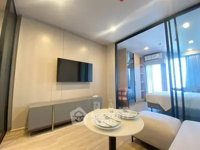 Modern apartment interior with open living room and bedroom, featuring sleek furniture and natural light.