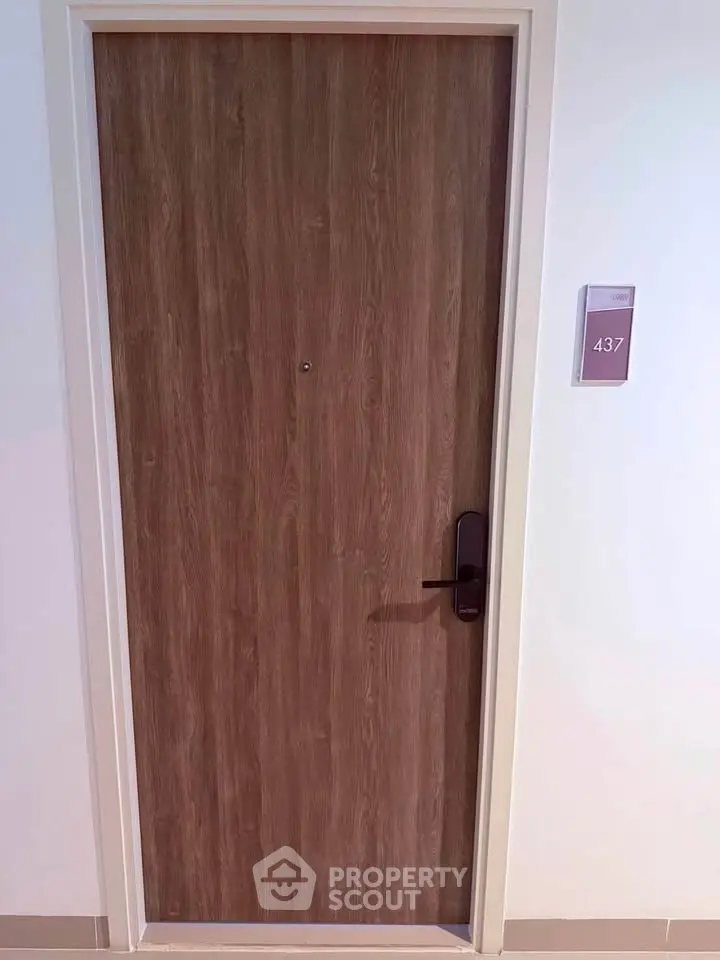 Modern apartment door with sleek wooden finish and room number 437, showcasing contemporary design.
