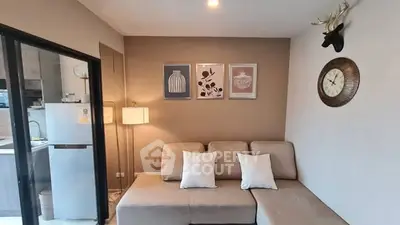 Modern living room with cozy beige sofa, stylish decor, and open kitchen view.