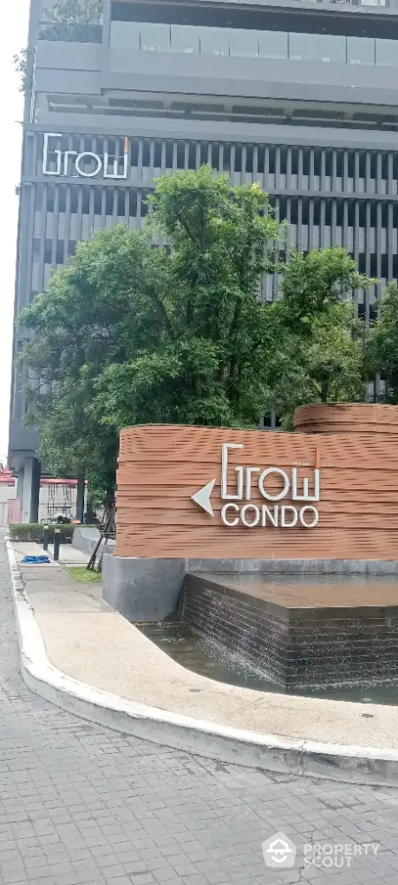 Modern condo building exterior with lush greenery and stylish signage.