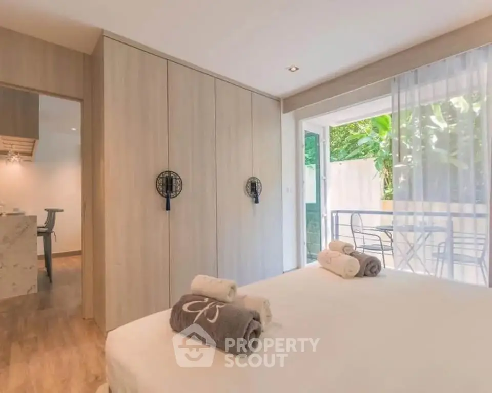 Spacious bedroom with modern decor and garden view, featuring elegant wooden wardrobe and cozy bedding.