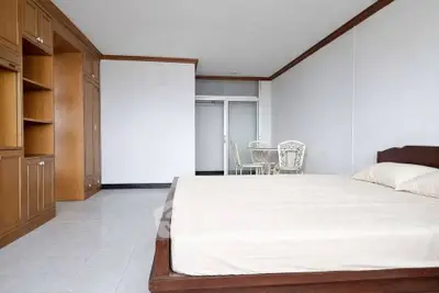 Spacious bedroom with wooden furniture and elegant decor, featuring a cozy bed and a small dining area.