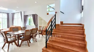 Spacious modern living room with elegant wooden staircase and dining area, perfect for family gatherings.