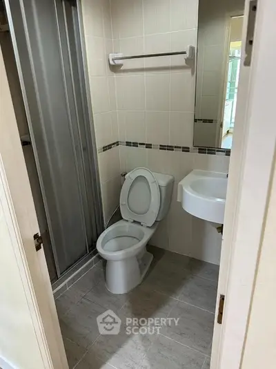 Compact bathroom with shower, toilet, and sink in modern apartment.
