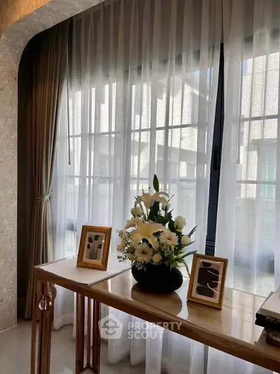 Elegant interior with sheer curtains and decorative console table in modern living space.