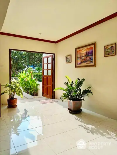 Bright entrance hallway with open door leading to lush garden view.