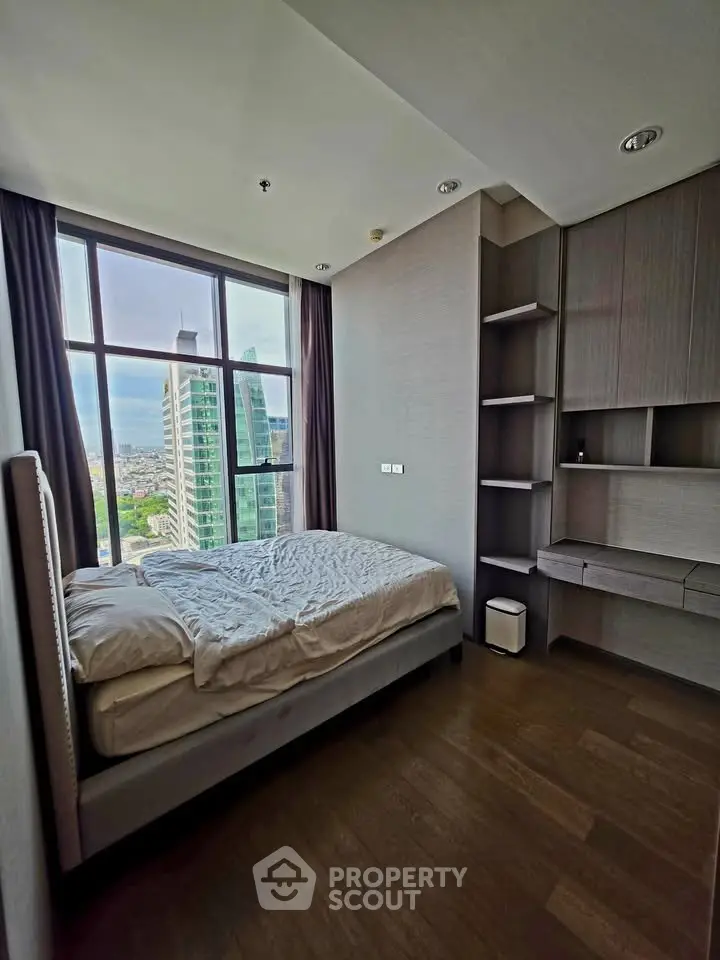 Modern bedroom with large window offering city view, featuring sleek built-in storage and cozy bed.
