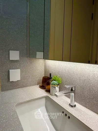 Modern bathroom with sleek sink and stylish decor in contemporary apartment.