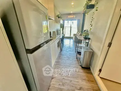 Modern kitchen with sleek appliances and open layout leading to a bright living area with balcony view.