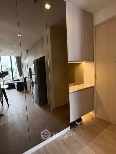 Modern apartment interior with sleek wooden flooring and built-in storage, featuring a view of the city skyline.