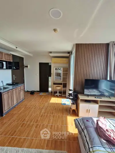 Modern studio apartment with open kitchen and cozy living area, featuring wooden flooring and ample natural light.