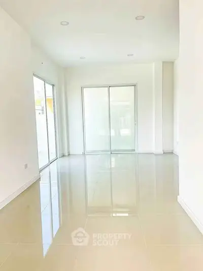 Spacious and bright living room with large windows and glossy tiled floors