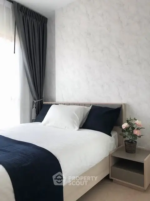 Cozy bedroom with modern decor and natural light, featuring a stylish bed and elegant curtains.