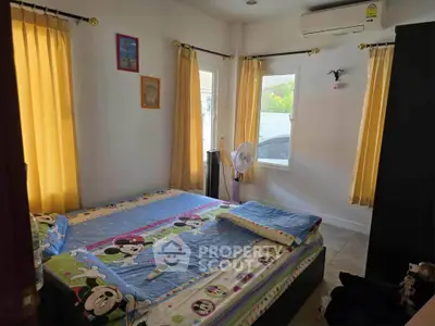Cozy bedroom with vibrant curtains and playful bedding, perfect for a cheerful living space.