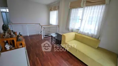 Bright living room with yellow sofa and wooden flooring, featuring large windows and modern decor.